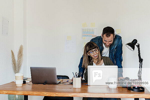 Lächelndes Geschäftspaar  das im Büro zu Hause gemeinsam am Laptop arbeitet