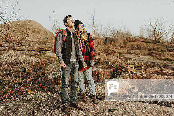 Junges Paar steht zusammen und bewundert die umliegende Landschaft während einer Herbstwanderung