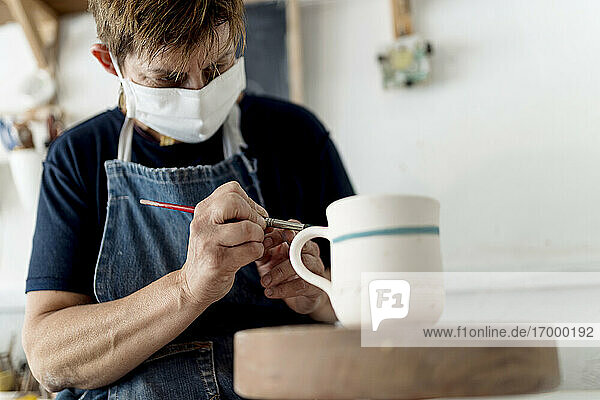 Künstlerin bemalt Tasse in Keramikwerkstatt