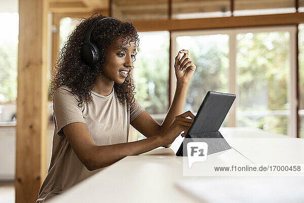 Geschäftsfrau mit Kopfhörern und digitalem Tablet  während sie zu Hause sitzt