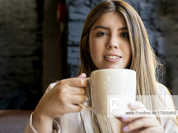 Young woman drinking coffee while sitting in cafe