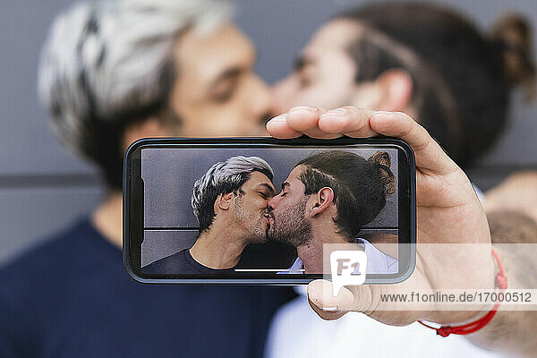 Man photographing while kissing gay partner in city