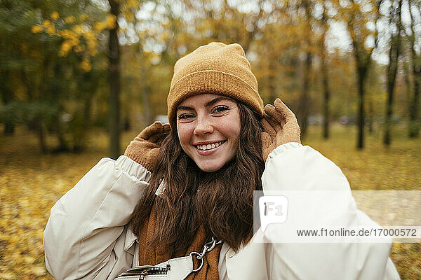 Happy young woman with hand in hair in autumn park