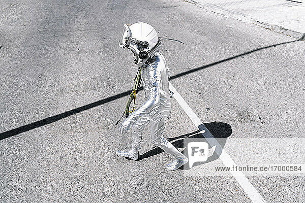 Junge im Astronautenkostüm läuft auf der Straße in der Stadt