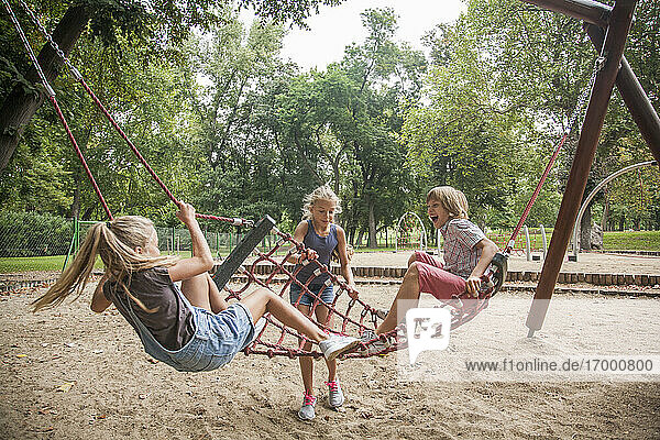 Junge und Mädchen haben Spaß beim Spielen auf der Seilschaukel auf dem Spielplatz