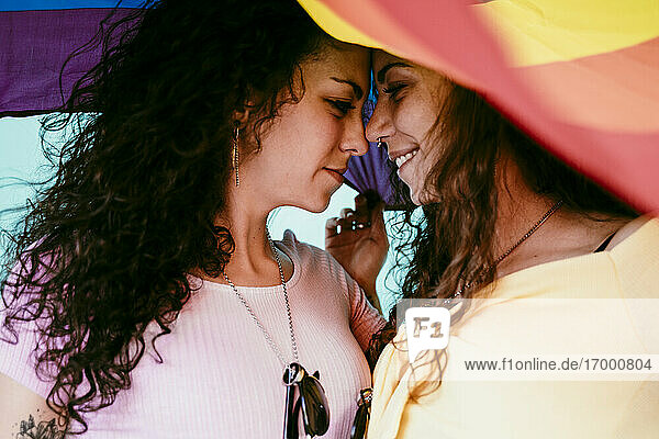Nahaufnahme eines lesbischen Paares mit Regenbogenfahne  das sich im Freien vergnügt