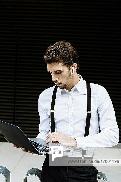 Stilvoller Geschäftsmann arbeitet am Laptop in der Stadt