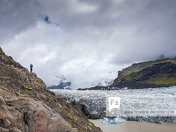 Mann steht auf einem Berg vor bewölktem Himmel am Svinafellsjokull-Gletscher  Island