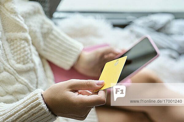 Woman shopping online with credit card through mobile phone at home