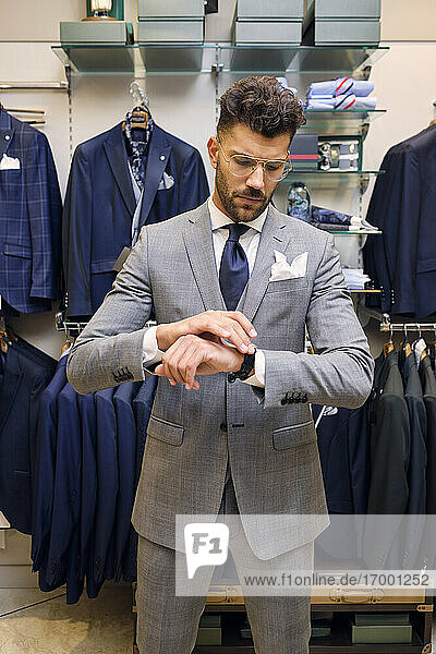 Man in gray suit checking time in tailors boutique