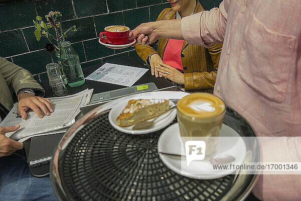 Mann serviert eine Tasse Kaffee in einem Straßencafé