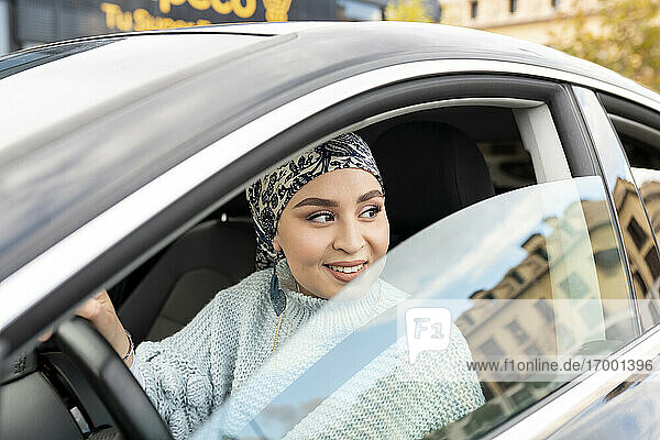 Lächelnde Frau  die wegschaut  während sie im Auto sitzt