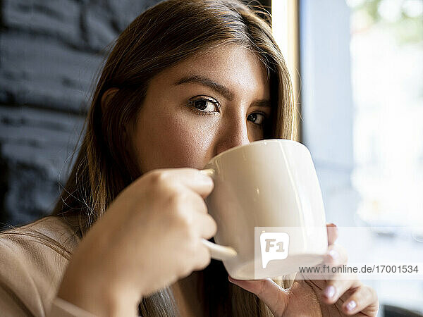 Woman staring while drinking coffee at cafe