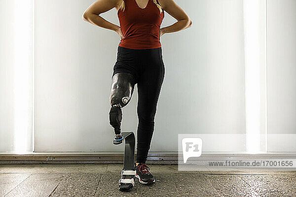 Athlete with prosthetic leg standing against wall in underpass