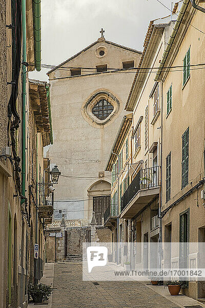 Spain  Mallorca  Pollenca  Empty alley between old town houses with church in background