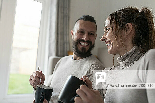 Happy couple having tea in mugs at home