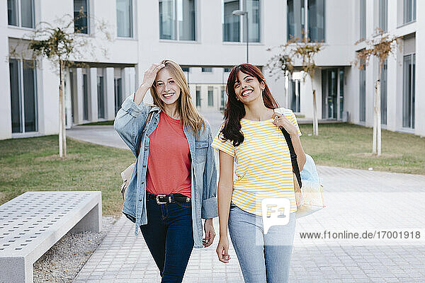 Fröhliche junge multiethnische Studentinnen  die über den Universitätscampus spazieren