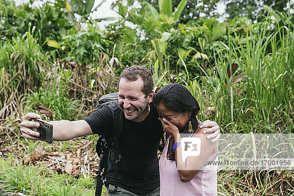 Smiling male tourist taking selfie with shy woman at Misahualli  Ecuador