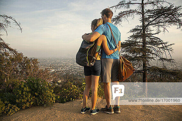 Paar  das sich umarmt  während es auf einem Berg stehend die Aussicht betrachtet