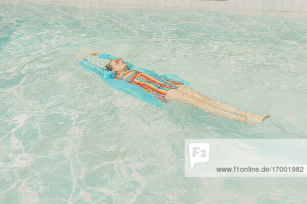 Bekleidete Frau schwimmt auf dem Wasser im Schwimmbad