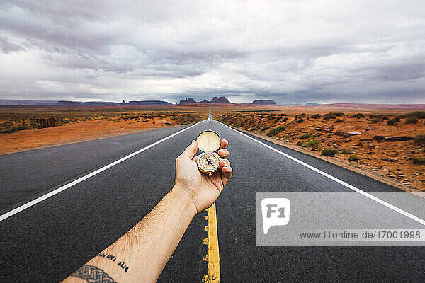 USA  Utah  Hand holding compass over road to Monument Valley