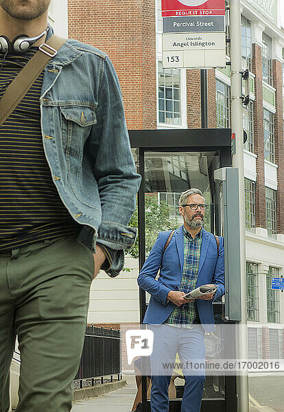 Mature man waiting while standing at bus stop