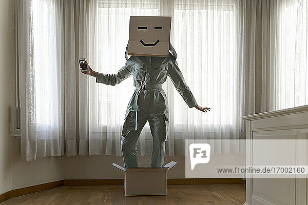 Woman wearing a cardbox on head with face and standing in box