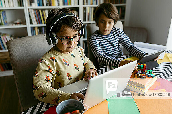 Junge zeigt Laptop an männlichen Freund auf Tisch zu Hause