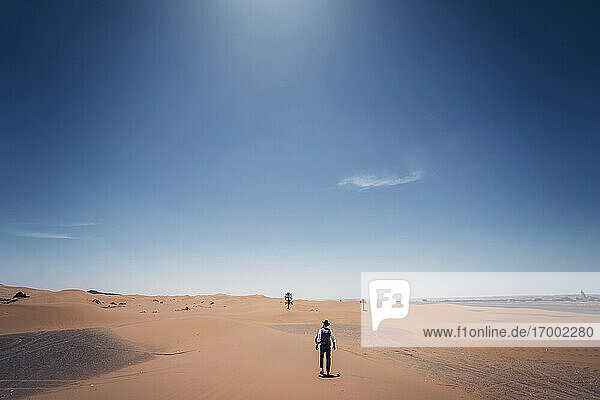 Lonely man with hat walking in the dunes of the desert of Morocco