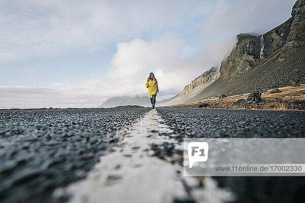 Island  Frau geht auf dem Mittelstreifen einer Landstraße