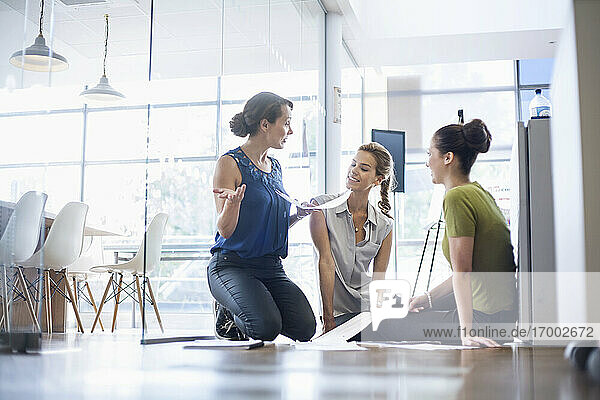 Unternehmerinnen besprechen Geschäftsideen auf dem Fußboden im Büro