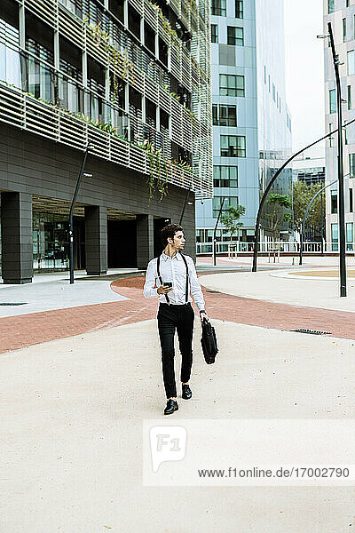 Stilvoller Geschäftsmann mit Smartphone beim Spaziergang in der Stadt