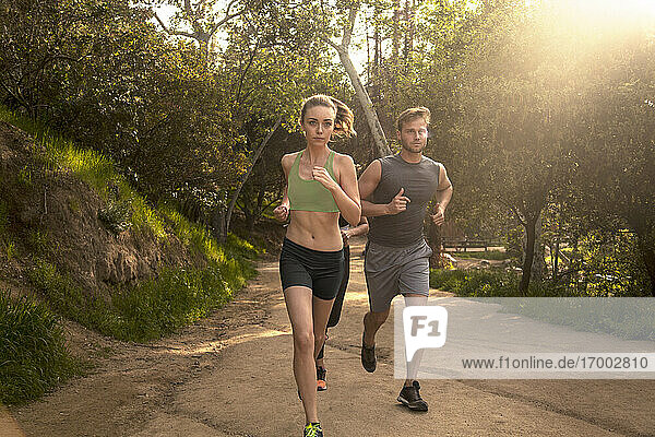 Athletes exercising while running together on footpath