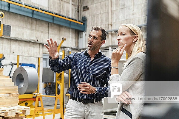Businessman explaining to female colleague while standing in factory