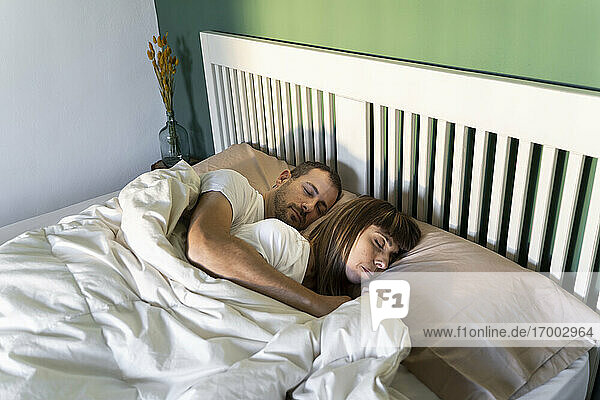 Mid adult couple sleeping together on bed at home