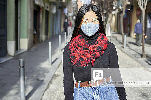 Junge Frau mit Gesichtsschutzmaske auf der Straße in der Stadt