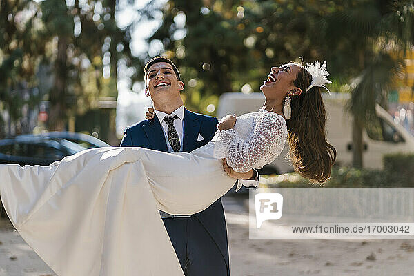 Junger Bräutigam holt fröhliche Braut im Park ab