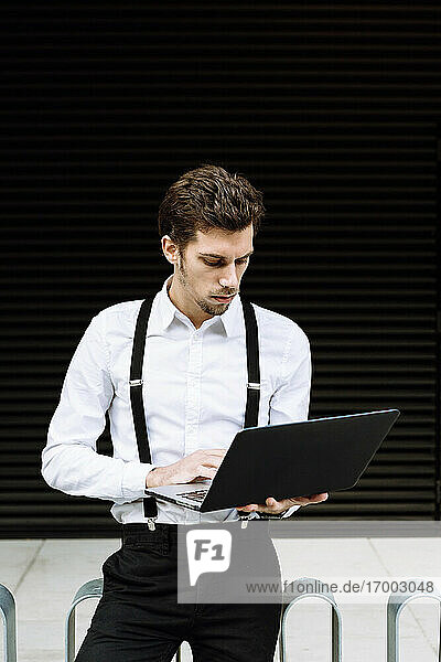 Stilvoller Geschäftsmann arbeitet am Laptop in der Stadt