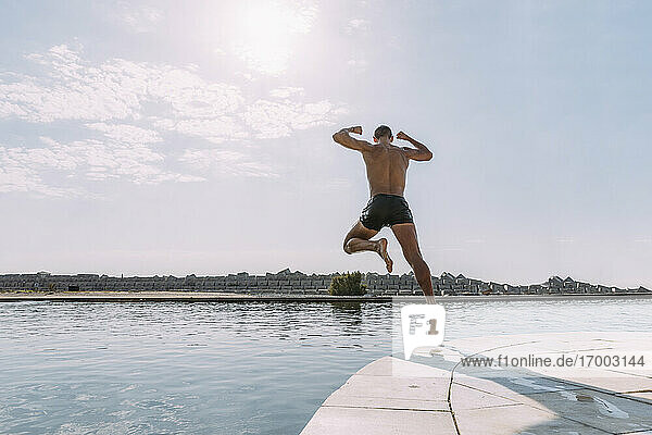 Young man jumping into water from a pier