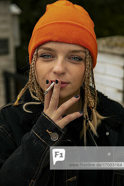 Fashionable young woman with blue eyes smoking cigarette