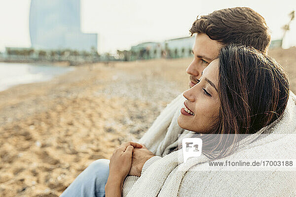 Junges Paar  das am Strand sitzt und wegschaut