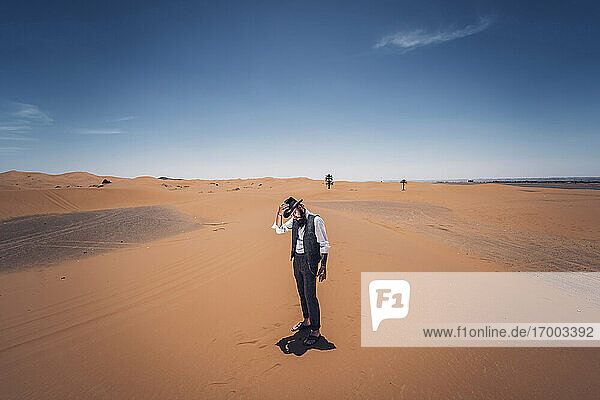 Man with a beard and hat in the dunes of the desert of Morocco