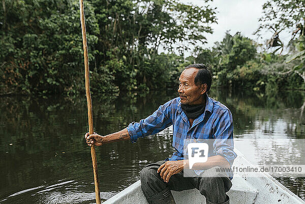 Senior Guarani man sitting in canoe at Napo River  Ecuador