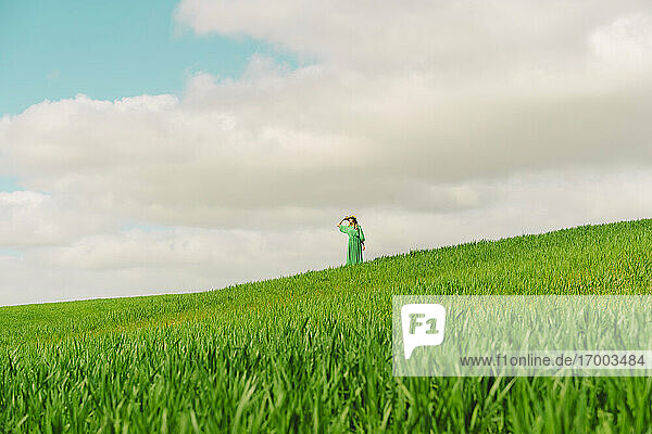 Woman wearing green dress standing on a field looking at distance
