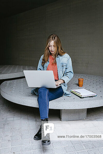 Schöne junge Studentin mit Laptop auf dem Campus