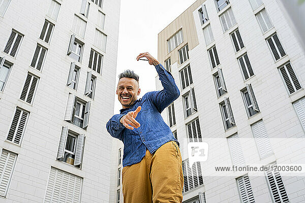Fröhlicher Mann tanzt vor weißen Gebäuden