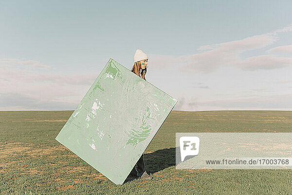Junge Frau hält grünes Bild auf trockenem Feld