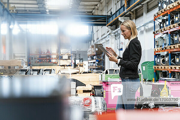 Female entrepreneur using digital tablet while standing in industry