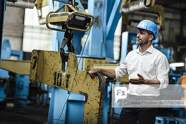 Businessman doing hand gesture while standing in factory