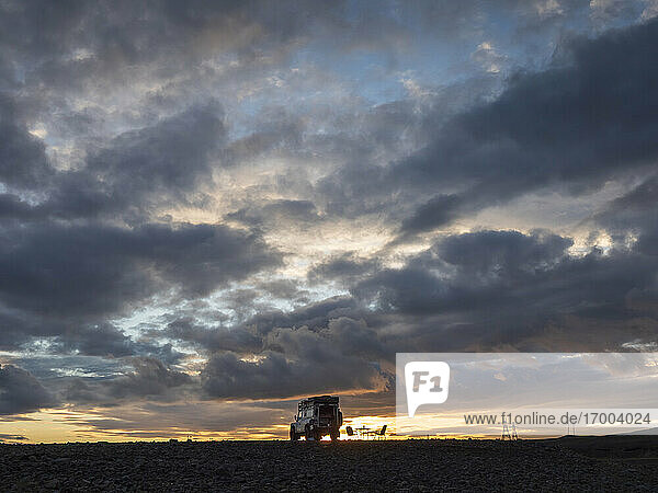 Gray clouds over off-road car parked in remote Icelandic location at dusk